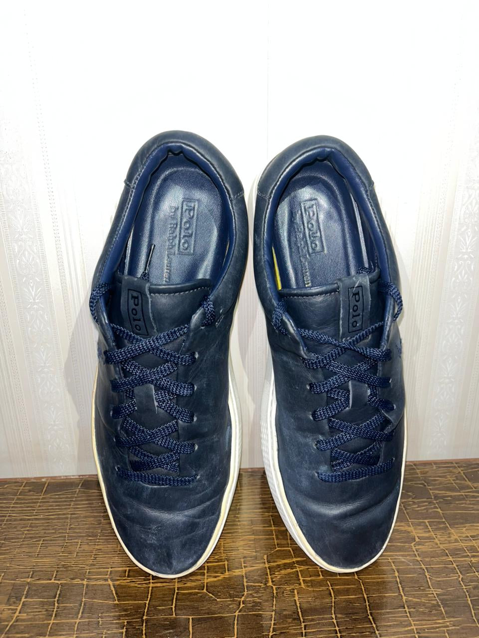 Top-down interior view of Polo sneakers highlighting the embossed leather insole and navy laces.