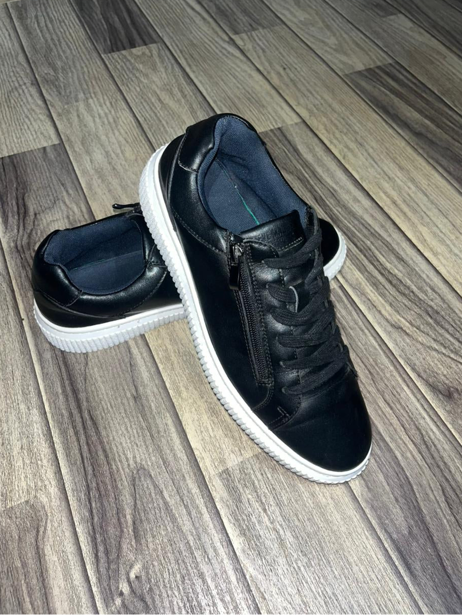 Steve Madden black street sneakers side view showing the metallic zipper and textured white sole.